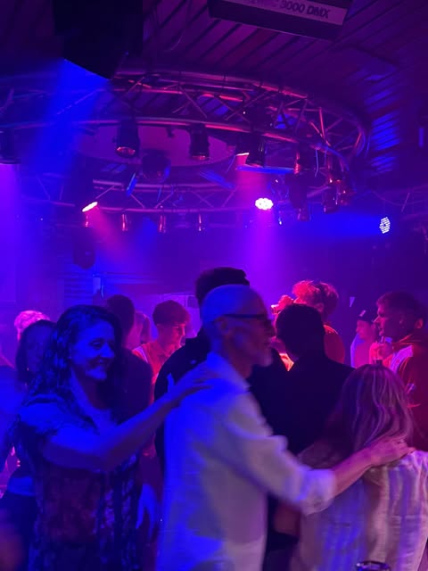 Vrienden dansen samen op de dansvloer onder paarse lichten