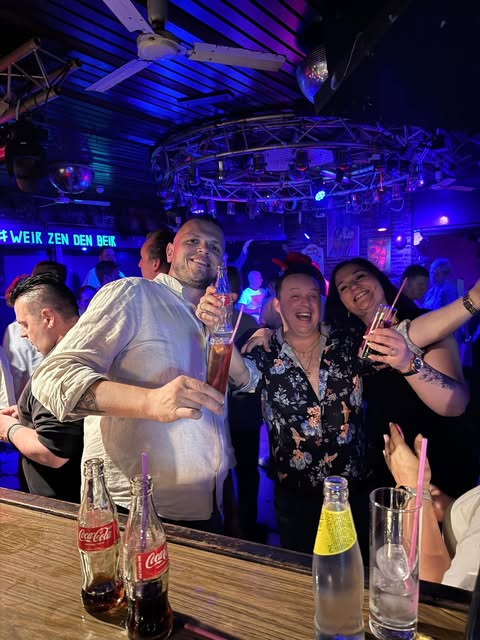 Vrienden heffen het glas met de slogan Weir zen den beir op de achtergrond